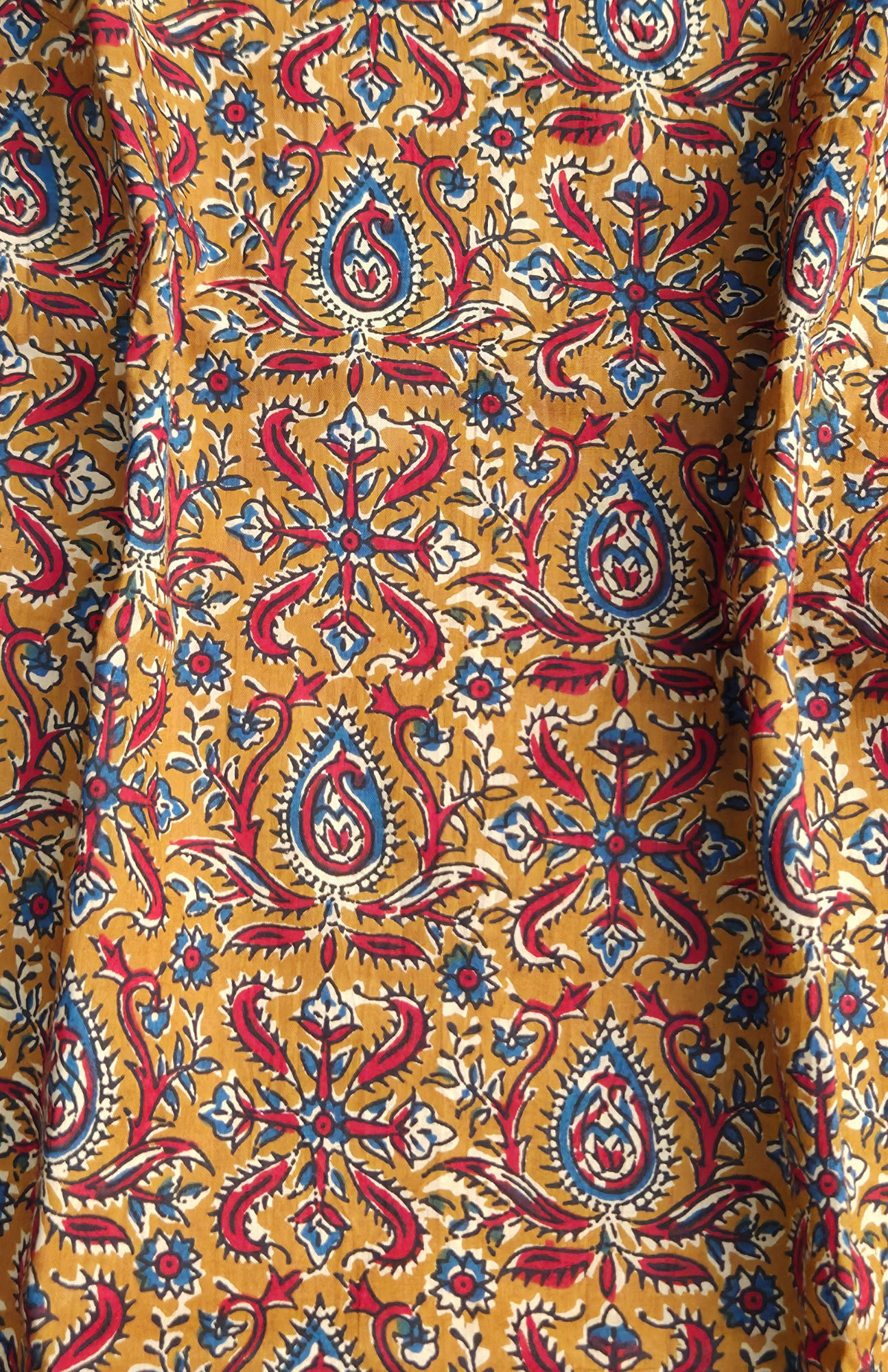 Close-up of a fabric with a colorful kalamkari pattern on a yellow background