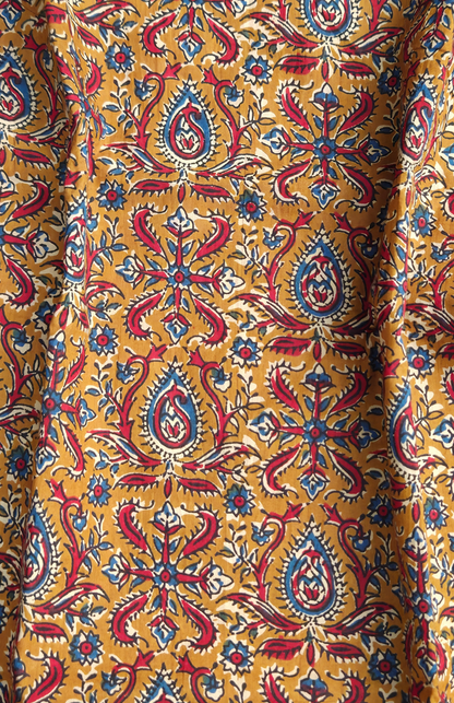 Close-up of a fabric with a colorful kalamkari pattern on a yellow background