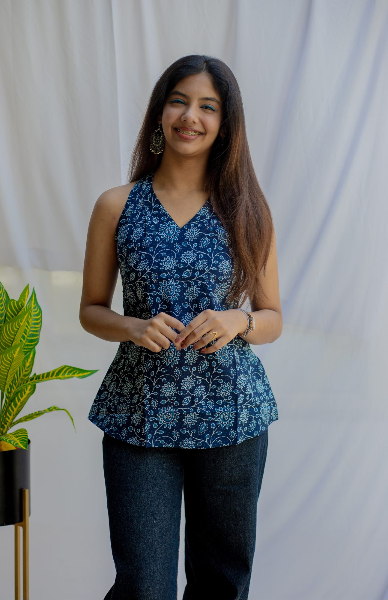 Woman wearing a blue floral peplum top standing against a white background